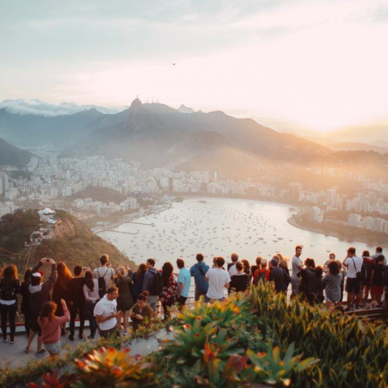 group of people standing facing lake view