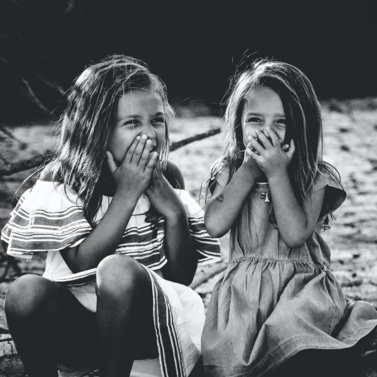 grayscale photography of two girls closing their mouths